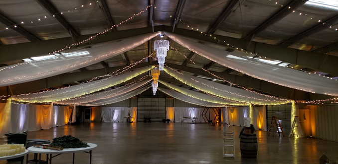 Wedding lighting at the Lake County Fairgrounds with amber and white up lighting. Three Chandeleirs by Duluth Event Lighting.