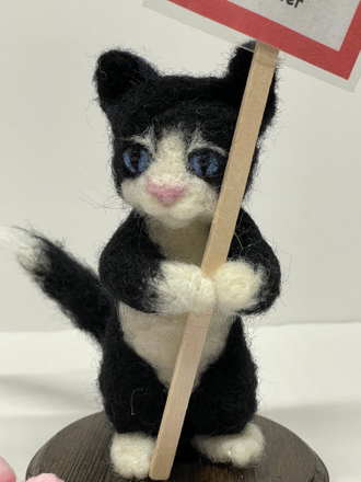 Needle felted black and white Kitten holding a protest sign.