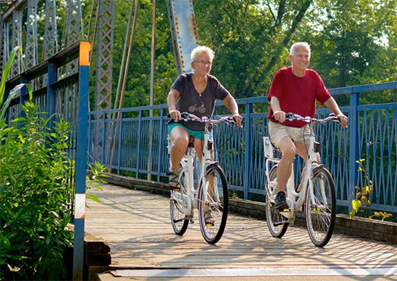 Man and women riding bike share bicycles across a bridge