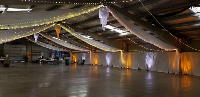 Wedding lighting at the Lake County Fairgrounds with amber and white up lighting with 3 chandeliers by Duluth Event Lighting.