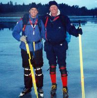 Two men wearing ice skates  and holding Nordic skating poles  are standing on icy lake that looks like glass