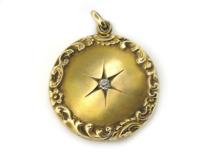 Turn of the Century locket in 14k yellow gold with a border of reposseand a center star set diamond.