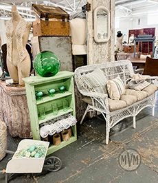 Primitive antique cabinet with chippy green paint paired with a vintage wicker bench and glassware. Amazing flea market finds!
