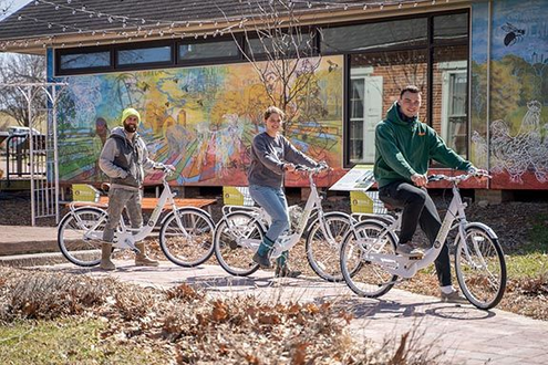 Bike Share riders in front of mural at college campus