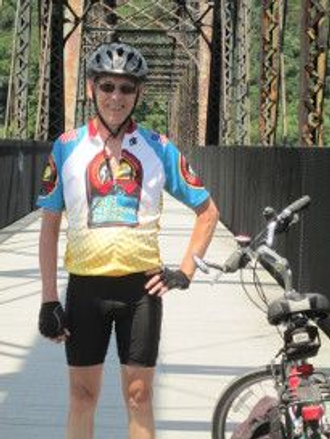 A very fit cyclist standing next to his bike on a bridge on the Allegheny River Trail