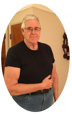 Picture of a tall, strong man, standing in his living room hold his right arm against his side