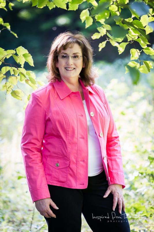 Susan Deren standing outside wearing pink jacket smiling.