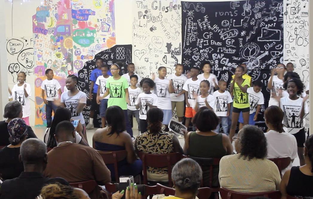 A group15 students standing and performing in front of an audience of parents andcommunity members.