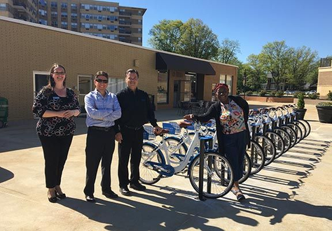 Property managers standing with bicycles at bike share station