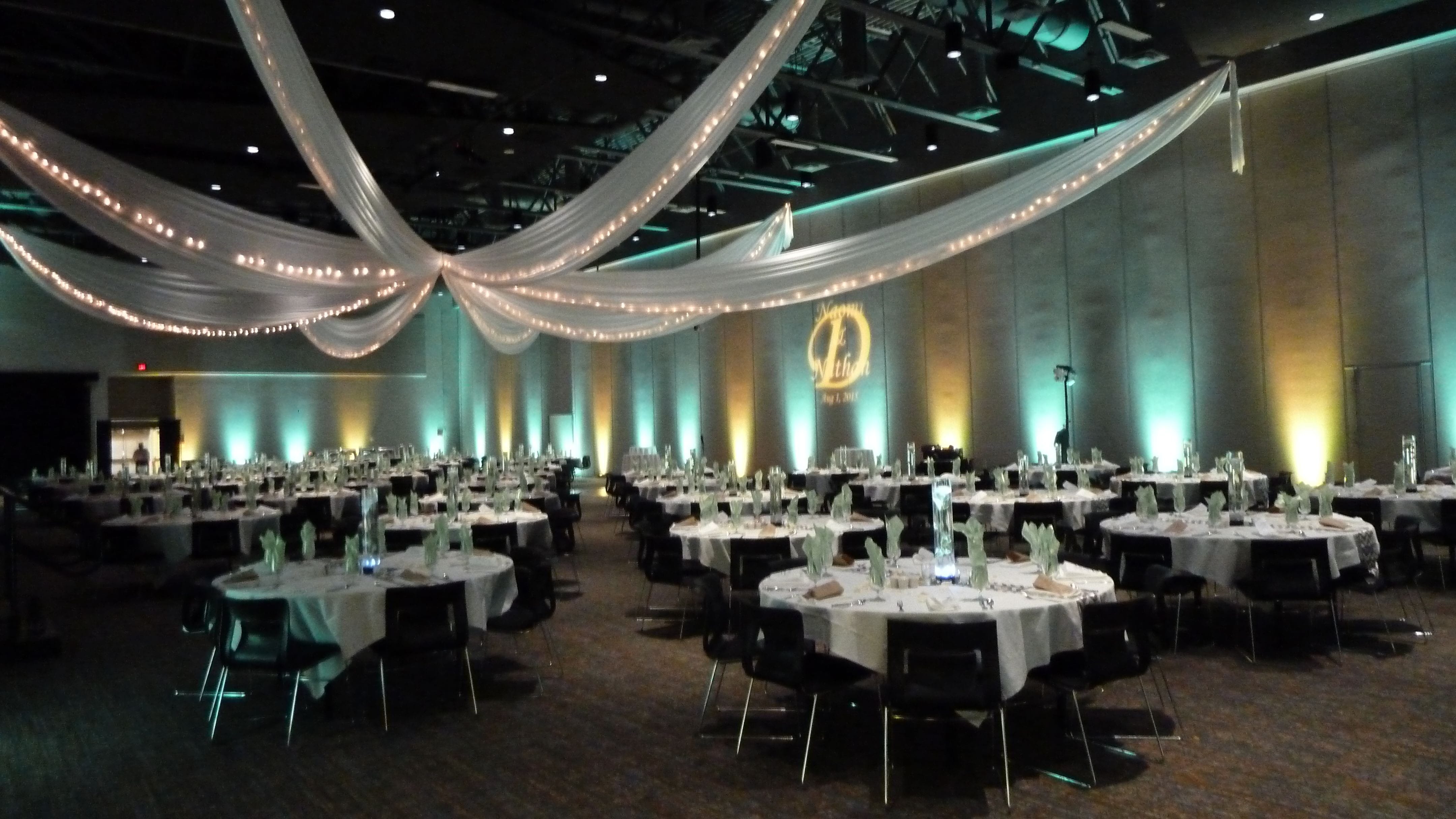 Up lighting in mint green and yellow with a wedding monogram by Duluth Event Lighting. Ceiling by @thevaultduluth
