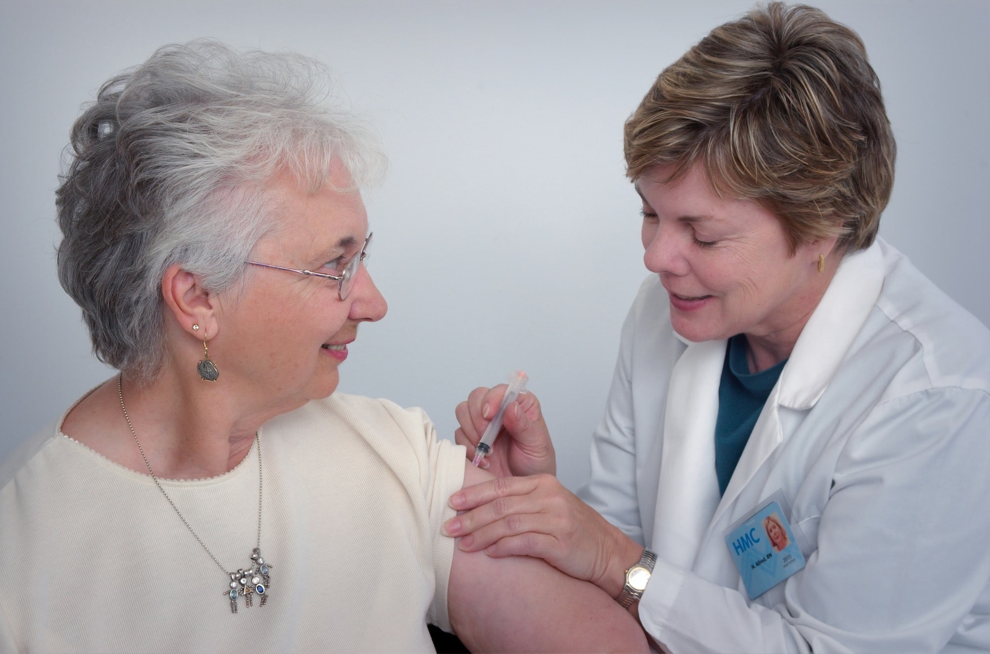 An image with a patient and a nurse administering a needle in her arm
