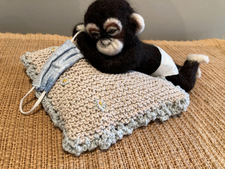 Needle felted chimp in diaper with mask and pillow.