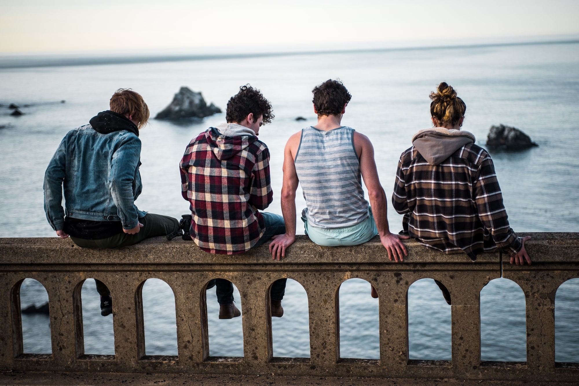 A group of four teenagers siting on a cement railing