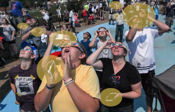 People trying to watch and capture a solar eclipse using conventional eclipse glasses.