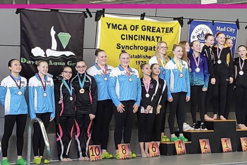 Minnesota Synchronettes at Podium to receive their Awards at YMCA Competition. sporting their custom swim team warmup suits insublimation