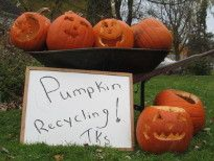 A wheel barrel full of jack-o- lanterns next to it is a white erase board that reads – Pumpkin recycling