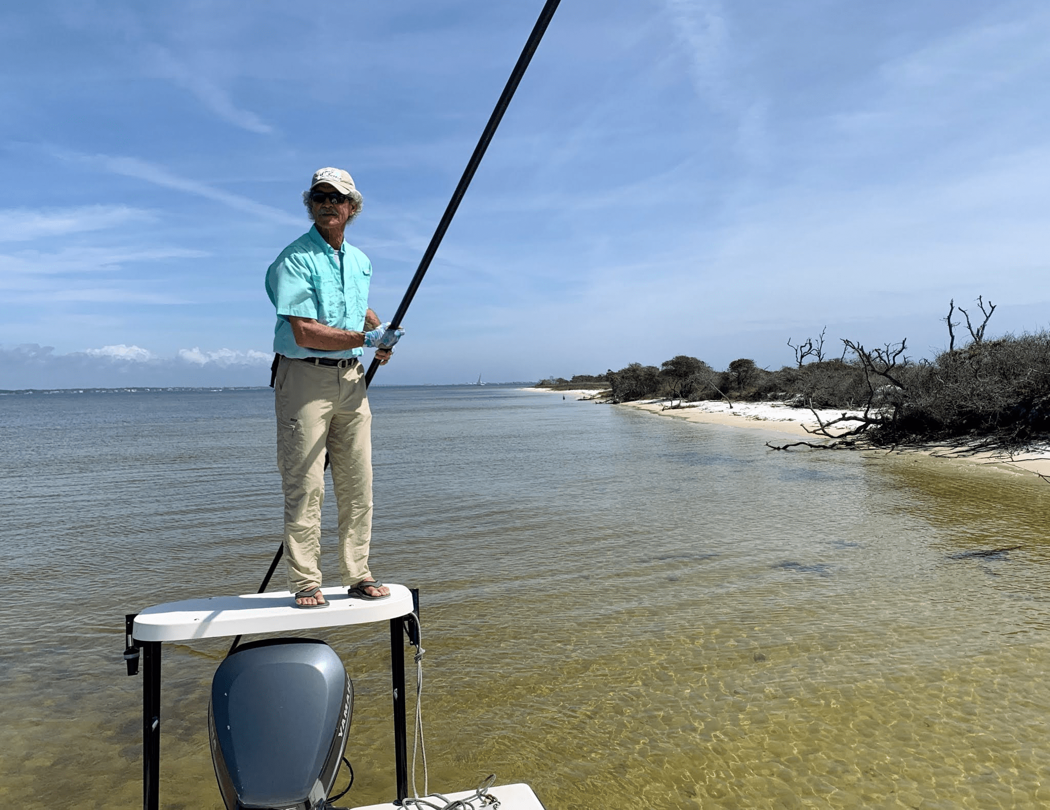 Captain poles skiff through clear shallow water in Santa Rosa Sound.