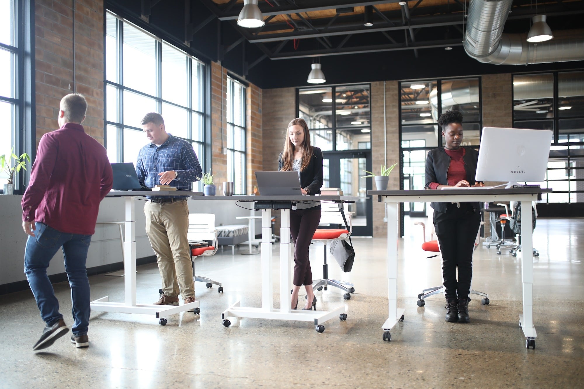 Four people working at standing desks