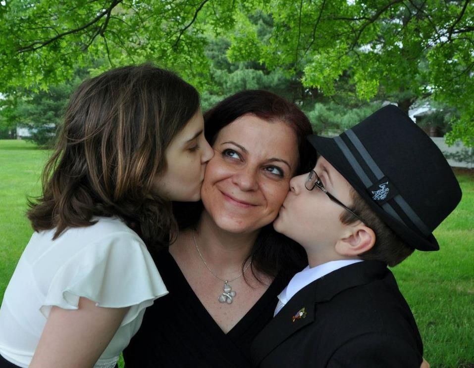 A empowered single mother blushes with love and pride as her two children kiss her cheeks.