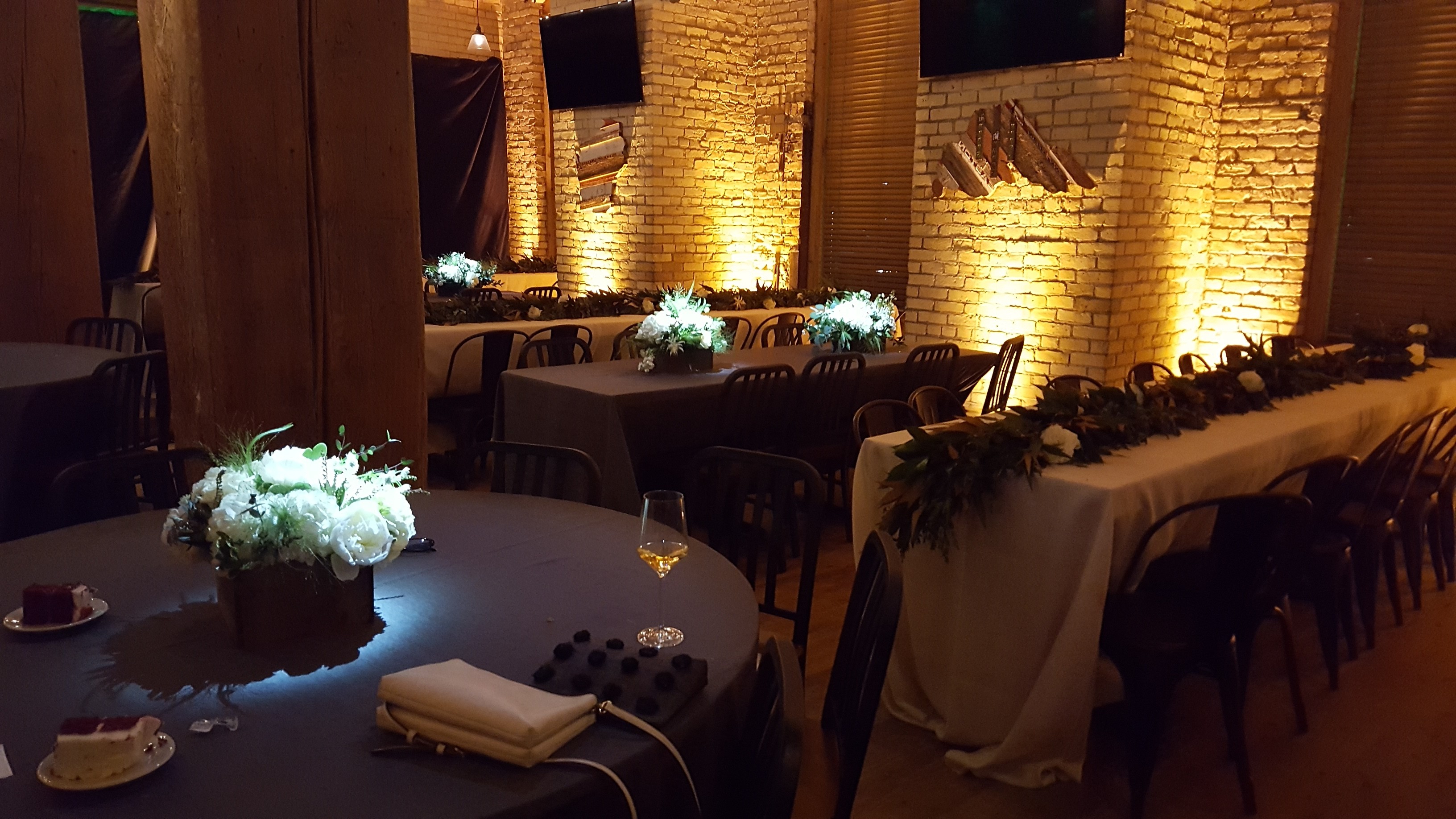 Wedding lighting at Hoops Brewery. Up lighting in gold with pin spots on flowers.