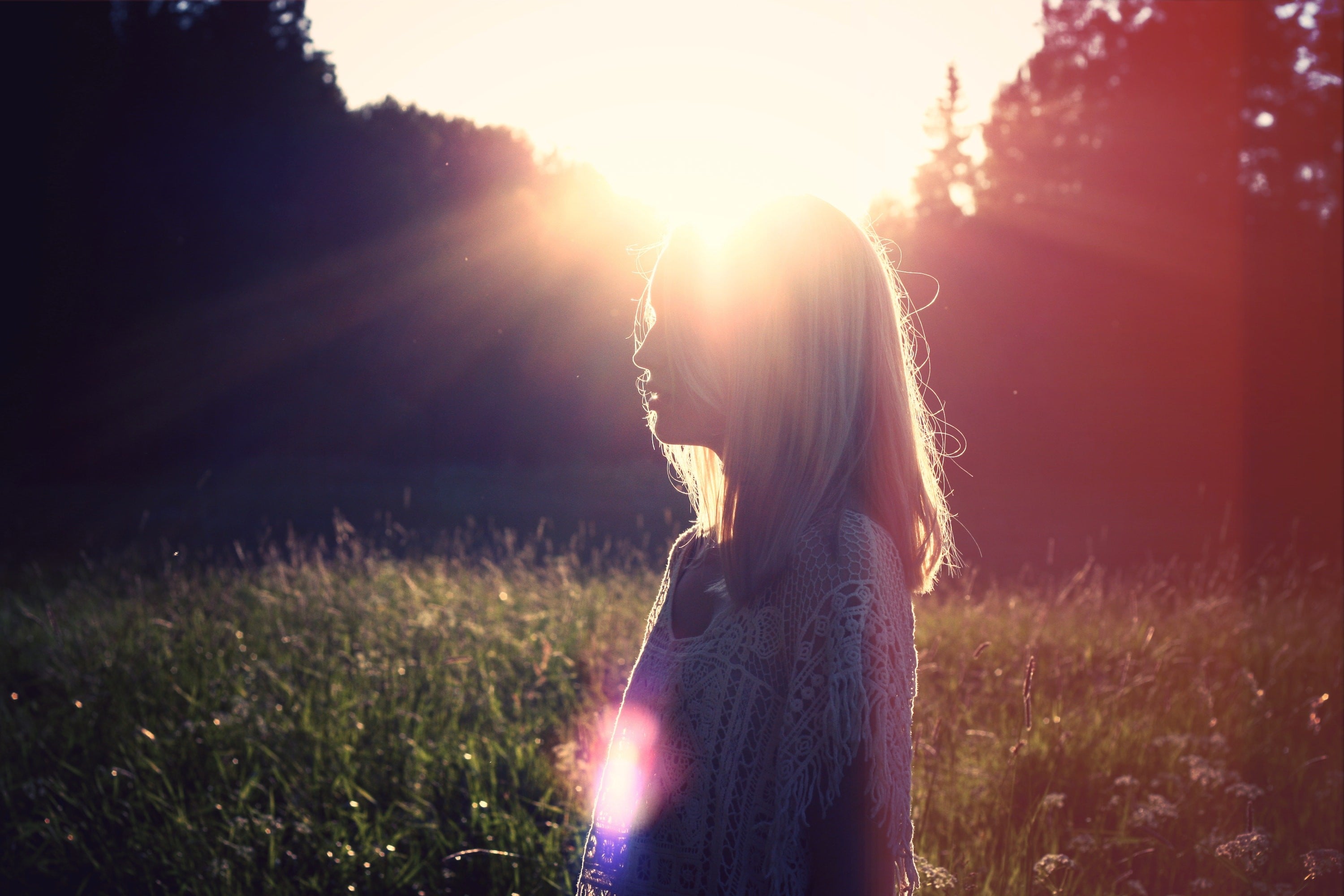 Woman outdoors with rays of sunlight behind her head