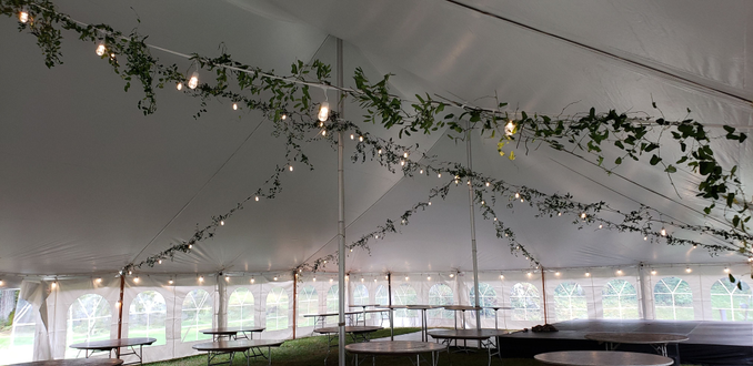 Tent wedding lighting. Bistro with greenery attached.