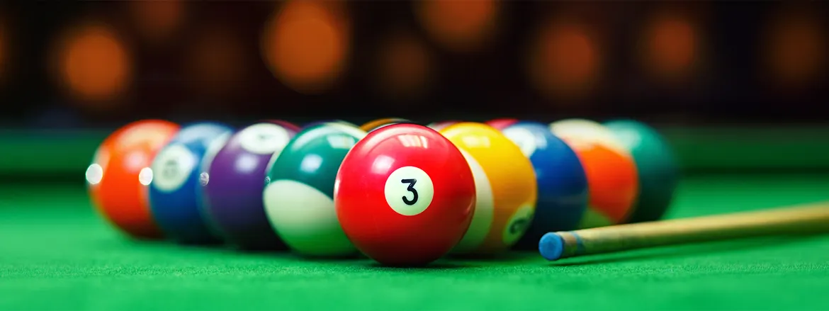 Colorful pool balls arranged on a green felt table, with a cue stick