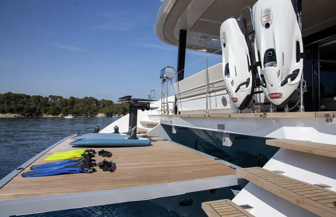 Yacht deck featuring scuba fins and diving scooters, with calm waters
