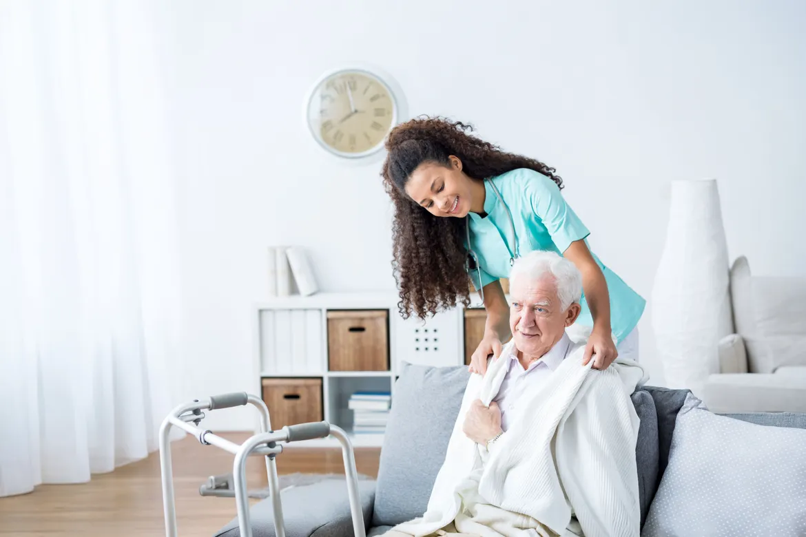 A caregiver assists an elderly man with a smile